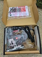 Jigsaw in factory bag with cord, blades and manual inside box