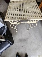 Top view showing lattice surface and scroll apron of cream metal square table