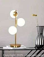 Stock image showing assembled three-globe brass table lamp