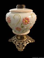 Front view of milk glass font with pink flowers, green scrolls and brass foot