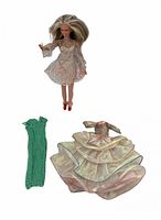 Front view of Barbie wearing mesh dress with two spare dresses laid out