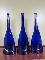 Front view of three cobalt blue glass vases standing upright