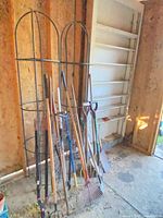 Overall view of two obelisk cages, stack of tools and wire tomato cages