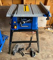 Front view of table saw on stand with accessories on floor