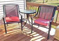 Two chairs and round glass table on deck