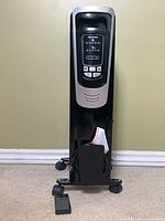 Front view of Pelonis radiator heater standing upright with remote in front