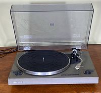Turntable with dust cover open showing platter and tonearm