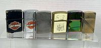 Six Zippo lighters lined up on acrylic stand, front view
