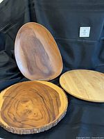 Front view showing all three wooden serving pieces: oval plate, live-edge plate, round Lazy Susan