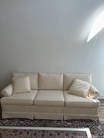 Front view of cream three-seat sofa against wall