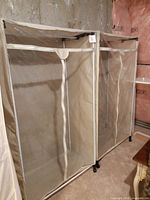 Two enclosed garment racks side by side