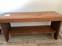 Full view of wooden bench showing top, legs and lower shelf