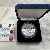 Medallion in capsule inside blue velvet case with certification card visible