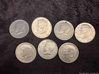 Obverse of seven Kennedy half dollars showing dates and wear
