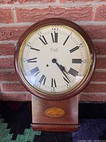 Front view of wood-cased wall clock showing dial and lower section