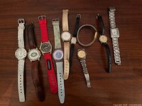All ten wristwatches arranged face-up showing dial styles, straps and case finishes
