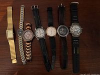 All seven wristwatches laid out side by side displaying cases, dials and straps