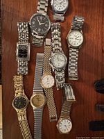 Overview of ten assorted wristwatches on wooden surface