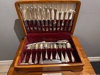 Overall view of open flatware chest showing multiple knives in lid and spoons, forks, serving pieces below