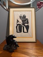 Framed linocut print and dolphin sculpture together on tabletop