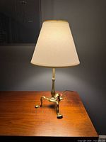 Full view of brass table lamp with shade on wooden surface