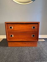 Front view showing teak nightstand with two drawers and square metal pulls