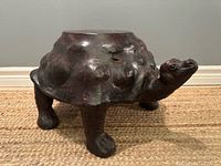 Side view of leather tortoise footstool showing shell, head, and legs