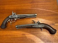 Both replica pistols side by side on wood surface