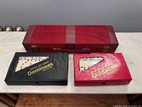 Closed red Rummy case, black domino case, red domino case