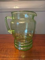 Full side view of green depression glass pitcher showing grape motif and handle