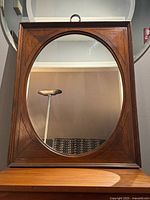 Full front view of mirror showing oval glass within rectangular walnut frame