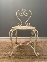 Full front view of wrought iron chair showing heart back and scroll legs