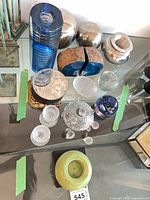 Full group shot of geode bookends, glass items, metal spheres and candle holders on glass table