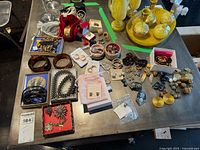 Overview of entire lot showing assorted necklaces, bracelets, rings, brooches, clip-on earrings spread on table