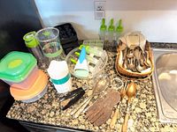 Full lot on countertop showing storage containers, pitcher, infuser bottle, ice cube molds, squeeze dispensers, utensil basket and loose utensils