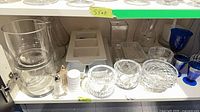 Shelf with majority of glass and crystal items including vases, bowls, goblets, tray, cups