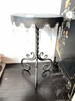 Full view of metal side table showing pendant detailing and tripod base