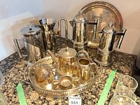 Full view of silver-plated coffee service, trays, French presses and moka pots on countertop