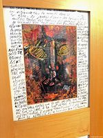 Close view of one artwork mounted in frame, shows wood finish and handwritten text background