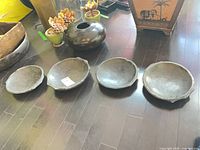 Four stone bowls laid out side by side on floor