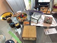 All items grouped on glass table showing six trinket boxes, glass candies inside silver box, bowl with stone hearts