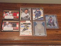 All seven hockey cards in protective sleeves and top loaders displayed on wooden surface