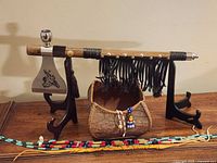 Overall view of tomahawk pipe on stand, bark bowl and bead necklaces