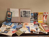 Full lot showing spread of approximately 25 vintage folded maps and aerial photo folder
