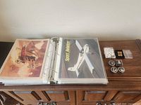 Open binder showing Sport Aviation magazine and vintage aircraft cover plus pins and magnets laid beside