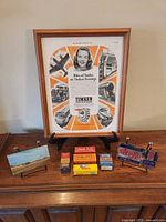 Entire lot on cabinet: framed Timken ad, five automotive parts boxes, two postcards on stands