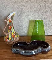 Group shot of ceramic ewer, kidney dish and green glass vase