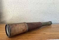 Telescope collapsed on surface showing leather grip and brass sections