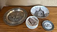 Overall view of pewter plate, porcelain Oldenburg plate, stack of small plates, small pewter plate