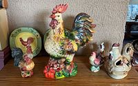 Group shot of all ceramic rooster items including plates, figurines, covered vessel